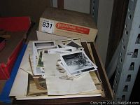 Photo showing a stack of vintage anonymous photographs with various images including portraits and scenes, alongside the closed Sculpstone soapstone carving kit box.