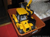 Two yellow Bruder construction vehicles including a front loader and an excavator in an orange bin