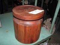 Solid cylindrical hardwood stand with rounded top, viewed from slight side angle showing wood grain and finish.