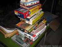 Stacked vintage plastic model kits and games shown from an angled top view, featuring colorful boxes with retro artwork.