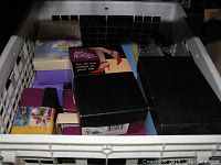 Overview of dozen boxed decorative shoes inside plastic container