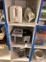 White two-slot toaster and handheld electric mixer on a shelf