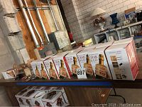 Photo showing 16 boxes with decorative holiday themed packaging marked 'Bottleneck Mini Grab & Go set of 4 holiday minis' lined up on table.