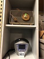 Shelf with two radios: vintage RCA Victor on top with brown textured body and circular gold dial; Sony radio below with digital screen and buttons.