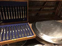 Opened wooden box showing 12 knives inside with blue felt lining