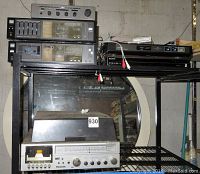 Photo showing multiple stereo components stacked on a shelf including the Sony DVD recorder, a Panasonic receiver with turntable on bottom, and Sanyo cassette decks and amplifier above.