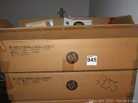 Two unopened boxes labeled 'Welf Small Wall Shelf' with the Blu Dot logo, showing product details and color selection options.