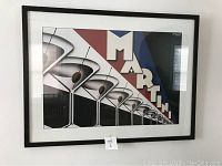 Framed Martini cocktail poster displayed in black frame with a white mat. Shows an artistic pattern with olives in martini glasses and large block letters spelling 'MARTINI'.