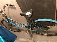 Side view of vintage Columbia turquoise bike showing frame, saddle, rear fender, and pedals.
