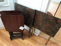 Four vintage Artex tray tables and wooden stand arranged together, showing tray finishes and stand design
