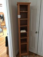 Front view showing overall bookcase height and six shelves, placed beside a white door.