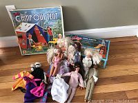 Photo of multiple vintage Barbie dolls and Ken doll with clothes and two boxed sets on wooden floor