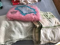 King Bates seashell patterned bedspread with a striped wool blanket and a packaged pink Styletone tufted chenille bedspread full size on top