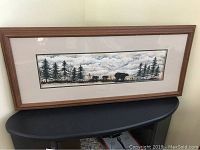 Framed panoramic artwork showing bears walking among trees and a cloudy sky.