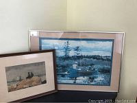 Two framed lithographs by Winslow Homer shown together on a black table in room corner