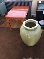 Photo showing large green pottery vase next to a wooden side table, highlighting size and shape.