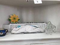 Shelf display with Zanetti glass bull, Crate & Barrel glass vase, mug, and flower napkin holder