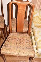 View of wooden dining chair back and patterned upholstered seat, showing overall style and fabric design.