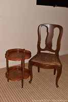 View of vintage enamelware tiered side table next to wooden chair with upholstered seat.