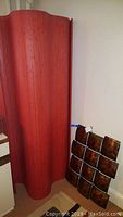 Front view of red wooden roll-up room divider leaning against wall