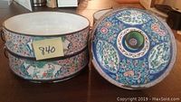Round enamel container with lid on table showing floral and figure designs in multiple colors