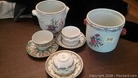Five porcelain items including two Limoge cups and saucers, one Christofle cup and saucer, a Villeroy & Boch piece, and one floral container.