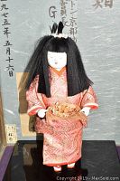 Full view of the Japanese doll showing entire figure in pink kimono and hair accessories, holding flower basket.