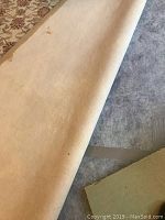 Close-up of the rug pad's underside showing beige cushioning material.
