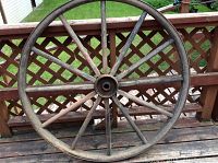 Full view of the vintage wagon wheel showing wooden spokes and steel rim.