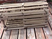 Angle view of wooden lobster trap showing slatted wood construction and wire mesh sides on wooden deck.