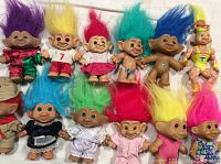 12 colorful collectible troll dolls arranged in two rows showing height about 5 inches each with varied outfits and hair colors.
