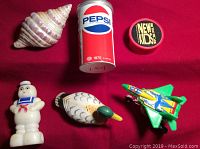 Top view of six vintage pencil sharpeners including seashell, Pepsi can, New Kids on the Block logo, Stay Puft Marshmallow Man, duck, and jet plane.