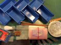 Photo showing 7 blue plastic storage containers, metal garden decoration, toy blaster, screwdriver set, chopsticks, and envelope sleeves.
