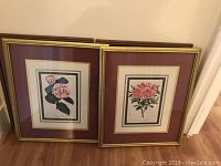 Two framed floral prints leaning against wall