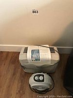 Photo of Multi-Tech air purifier and Rite Temp fan heater placed on wood floor against a wall with a lot sticker above.