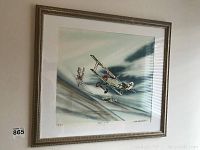 Framed print showing two Fokker D VII biplanes in aerial battle scene, with sky and cloud background.