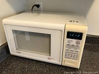 Front view of a white Citizen microwave oven plugged in, showing digital display and control buttons.