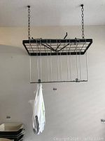 Photo of the pot rack with attached stainless steel glass rack and extra pieces in a plastic bag hanging from it