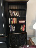 Photo showing upper open shelving section painted black with gold edges, holding books.