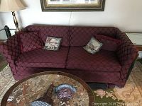 Front view of a burgundy custom upholstered 2-seater sofa with four cushions and visible patterned fabric.