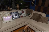 Nine decorative pillows arranged on a beige sectional sofa including patterned, faux fur, leopard print, and sequined pillows