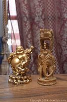 Both figurines on a wooden surface with curtains in background.