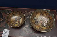 Two square-shaped Satsuma bowls placed side by side on a patterned surface showing detailed hand-painted scenes and gold leaf decoration.