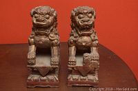 Front view of the two Foo Dogs side by side on a table with an orange background
