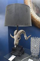 Front view of faux ram skull lamp with black shade, showing overall design and base.