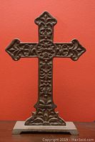 Front view of cast iron cross showing overall shape, floral patterns, and base detail.
