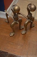 Pair of brass door stops placed on wooden floor, showing overall design and condition.