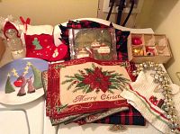 Photo showing assortment of Christmas decor including Santa hat, stocking, Christmas glass ornaments, placemats, and plate with reindeer design.