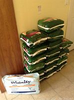 Stack of Depend women’s underwear packages and one Dignity pad package showing quantity and packaging.