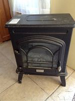Front view of the black metal electric fireplace with stove style design and glass door.